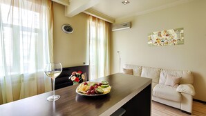 A dining area with a table, a plate of fruit, and a glass of white wine. - Sherborne ApartHotel (Kyiv)