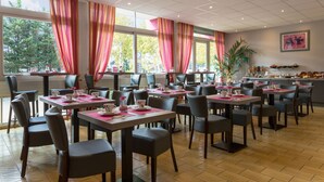En restaurang med flera bord och stolar, stora fönster med gardiner och utsikt över träd utanför.