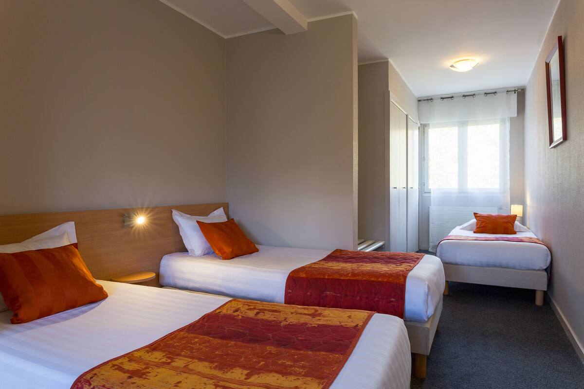 A hotel room with two beds, each with a red and white bedspread, and a wooden headboard.