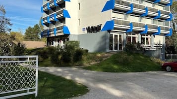 A multi-story building with a modern architectural design, featuring balconies and a gated entrance.
