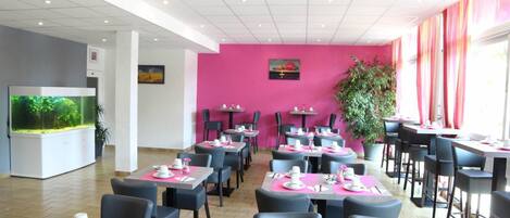 A restaurant with tables set for dining, chairs, and a large fish tank in the background.