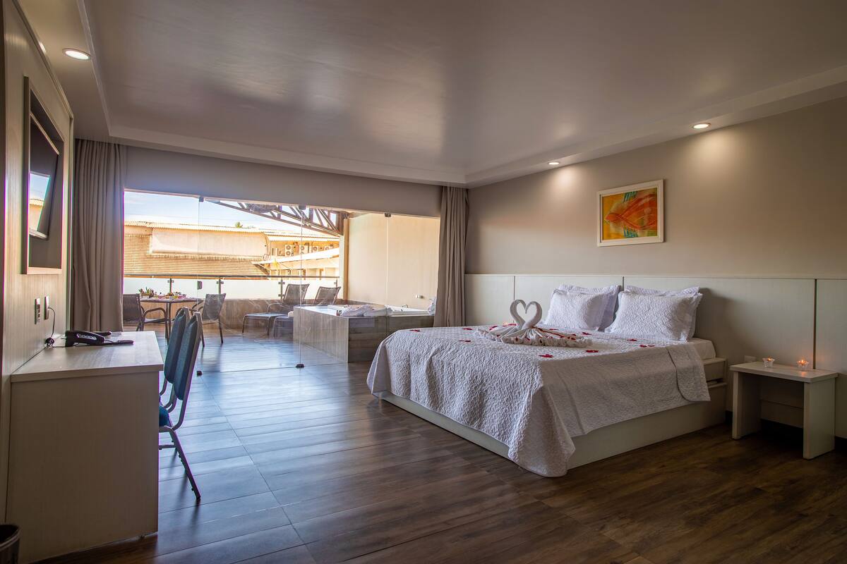 A hotel room with a bed, a desk, and a dining area.