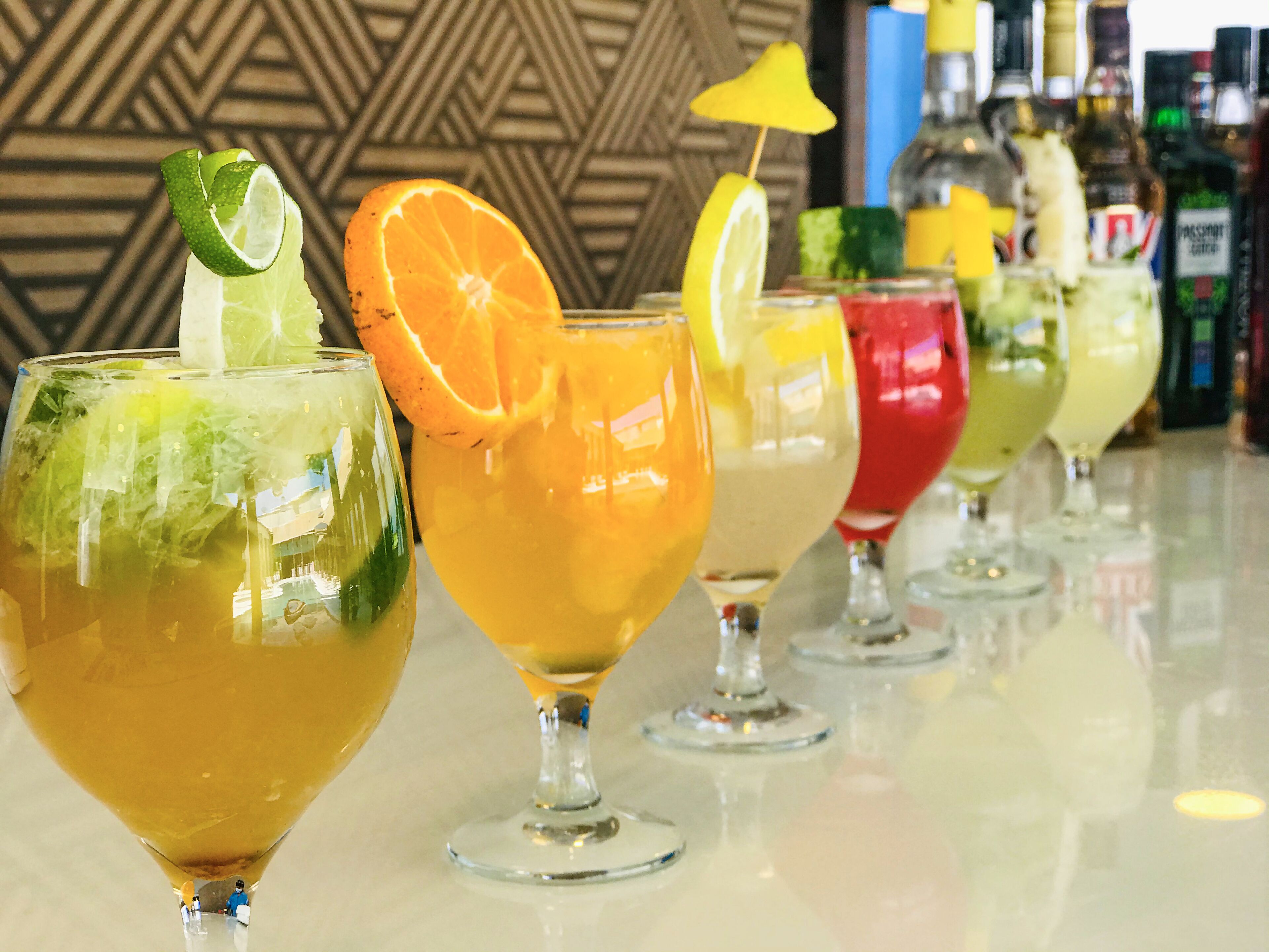 Um bar com várias bebidas, cada uma decorada com frutas e uma fatia de limão.