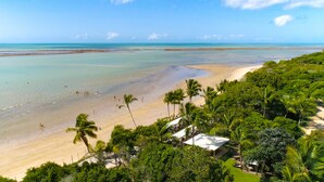 A beach with a clear view of the ocean, palm trees, and a few beach umbrellas. - Nauticomar Resort All Inclusive & Beach Club (Porto Seguro)