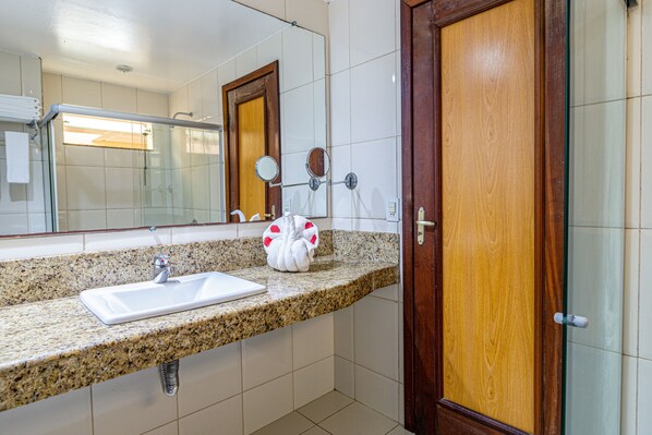 A bathroom with a granite countertop, a white sink, and a wooden door.