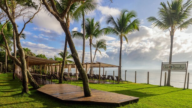 A beachside resort with a wooden deck, palm trees, and a sign reading "Club Paradiso." - Nauticomar Resort All Inclusive & Beach Club (Porto Seguro)
