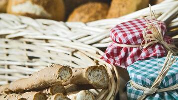 Un panier rempli de différents types de pain, notamment des baguettes et des petits pains, et décoré de serviettes à carreaux.
