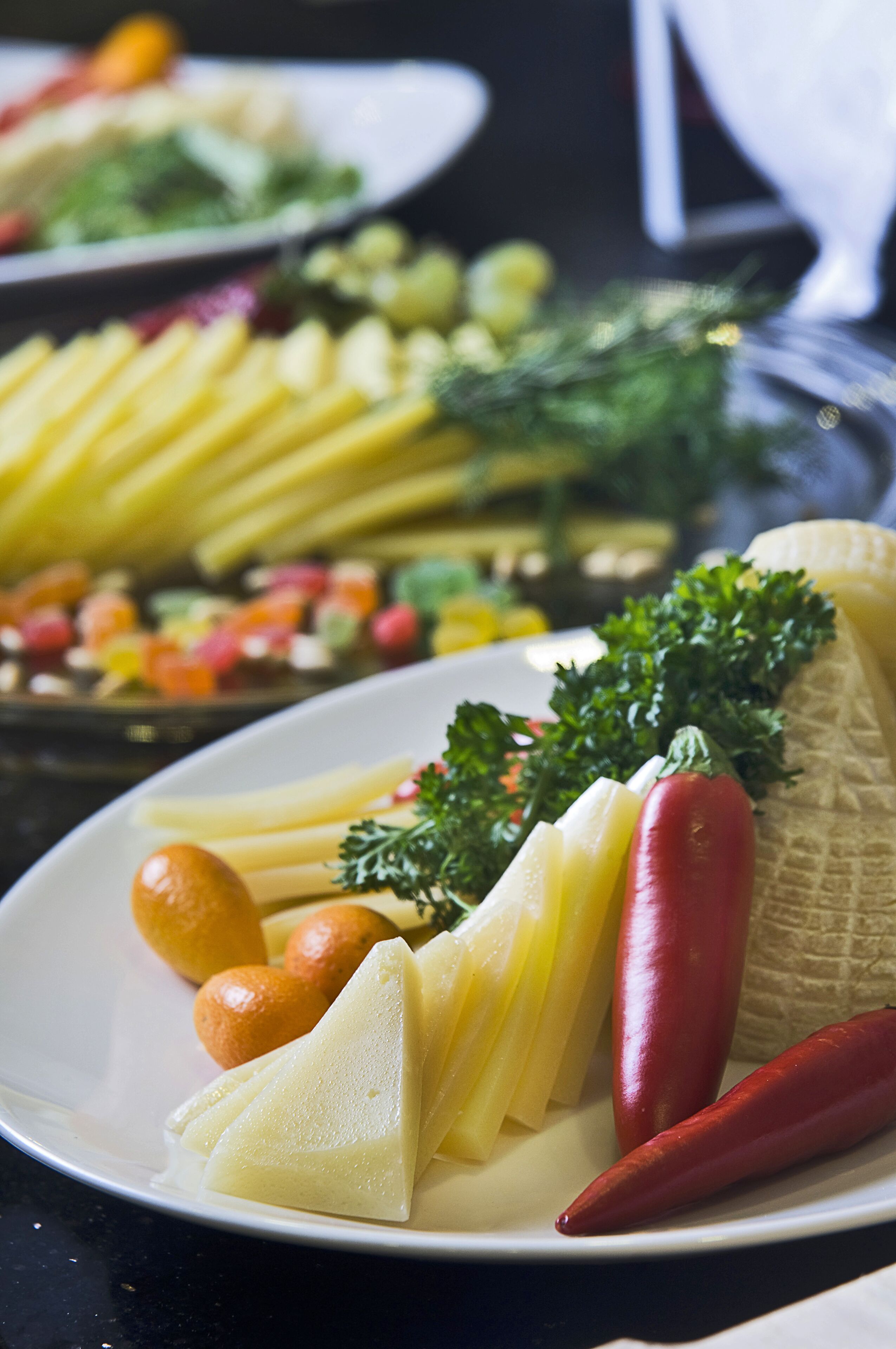 Ein Teller mit Scheibenkäse, einer roten Chilischote und einem Ohr Mais.