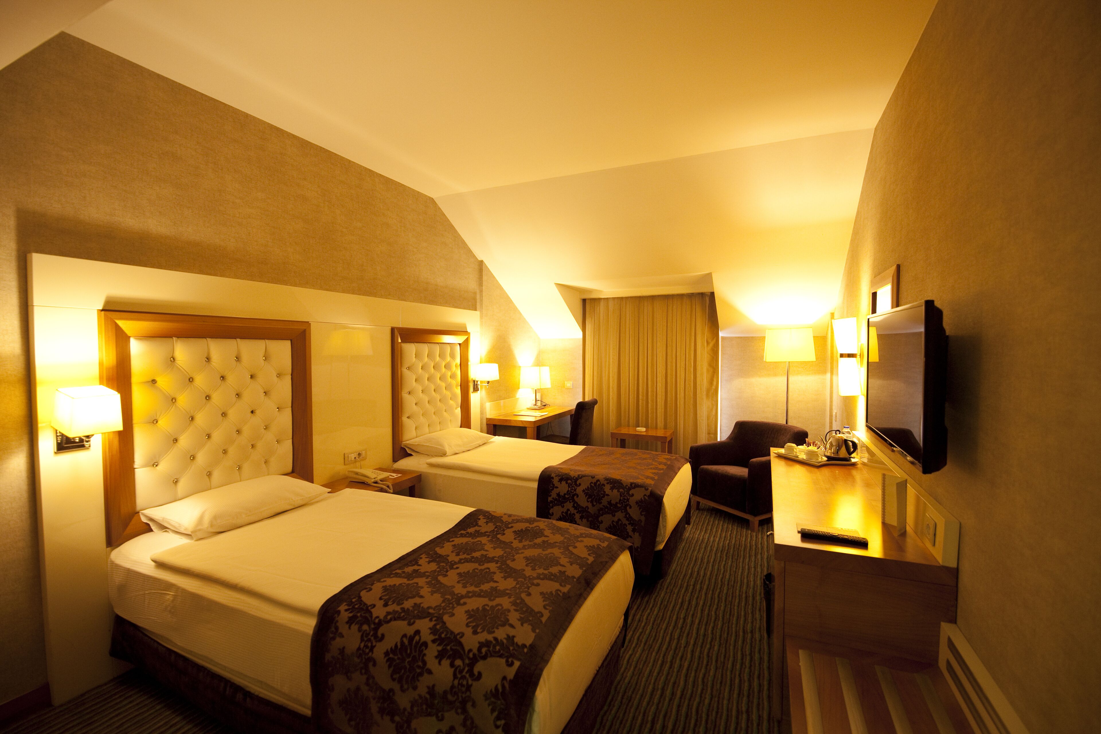 Une chambre d’hôtel avec deux lits, un bureau, une chaise, une télévision et une lampe.