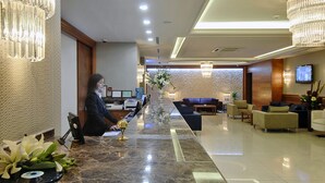 A hotel reception area with a marble counter, receptionist, seating area, and modern decor. - Tugcu Hotel Select (Bursa)