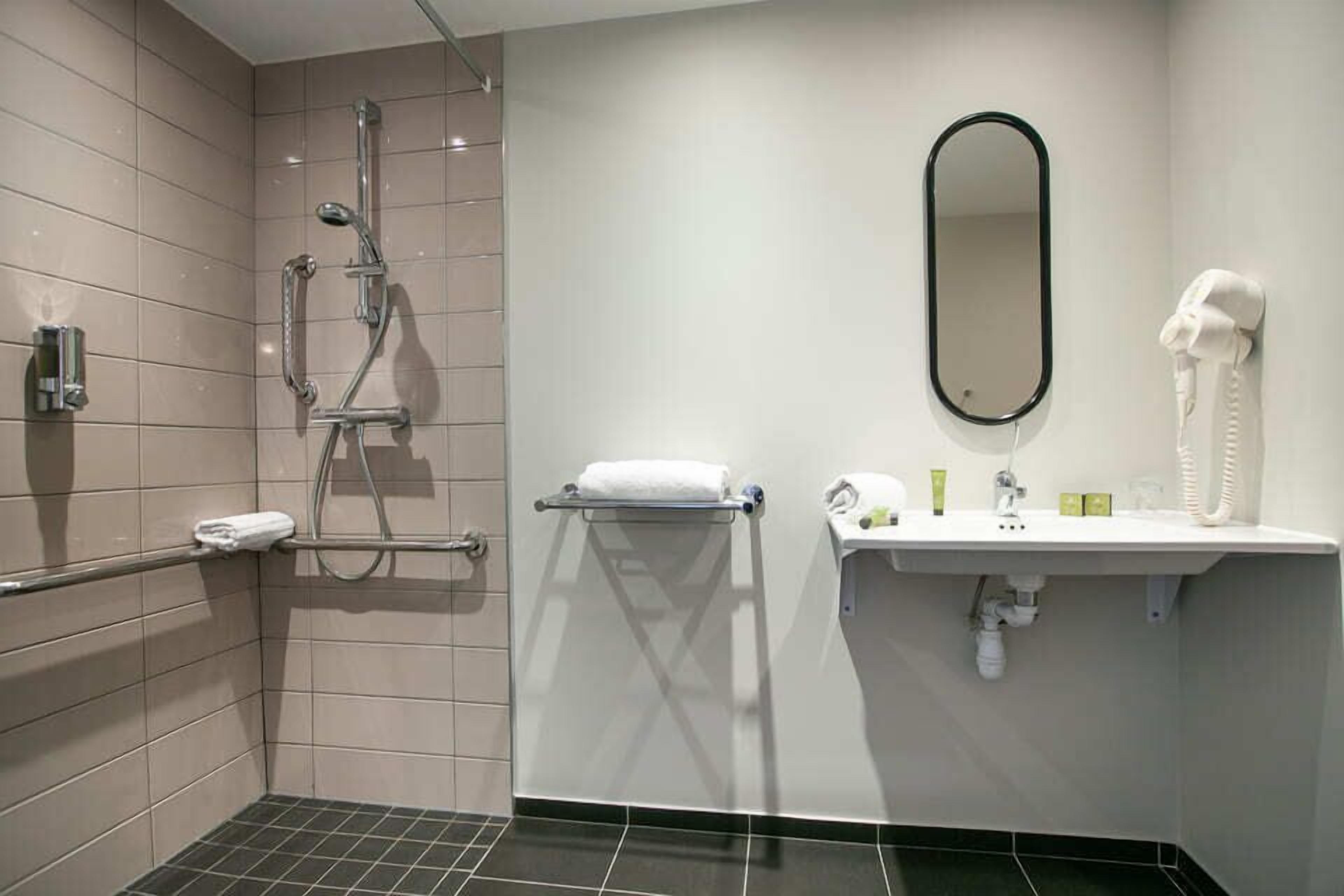 A modern bathroom with a shower, a sink with a mirror, and a hairdryer.