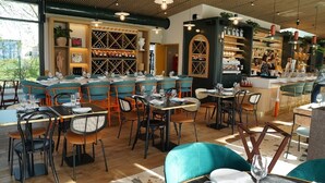 Un restaurante con zona de bar, estanterías de madera para vinos y vistas al exterior.