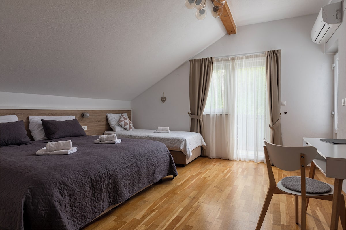 A bedroom with a large bed, a smaller bed, a desk, and a chair.