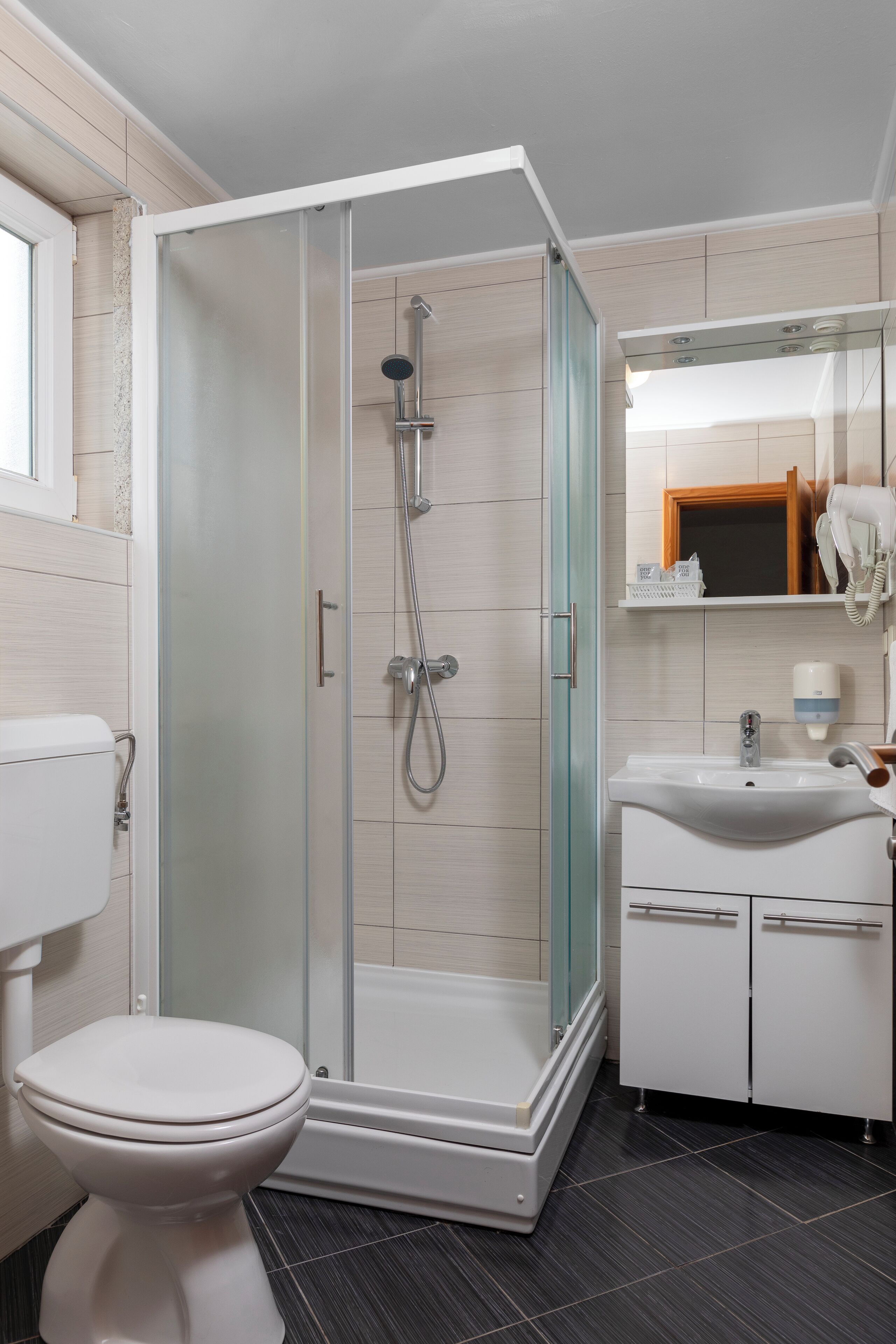 A modern bathroom with a glass-enclosed shower, a white toilet, and a sink with a mirror above it.
