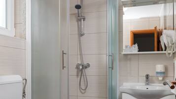 A modern bathroom with a glass-enclosed shower, a white toilet, and a sink with a mirror above it.