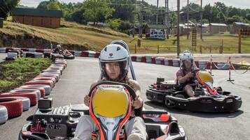 Kart de corrida em pista, com barreiras de segurança e área gramada ao fundo.