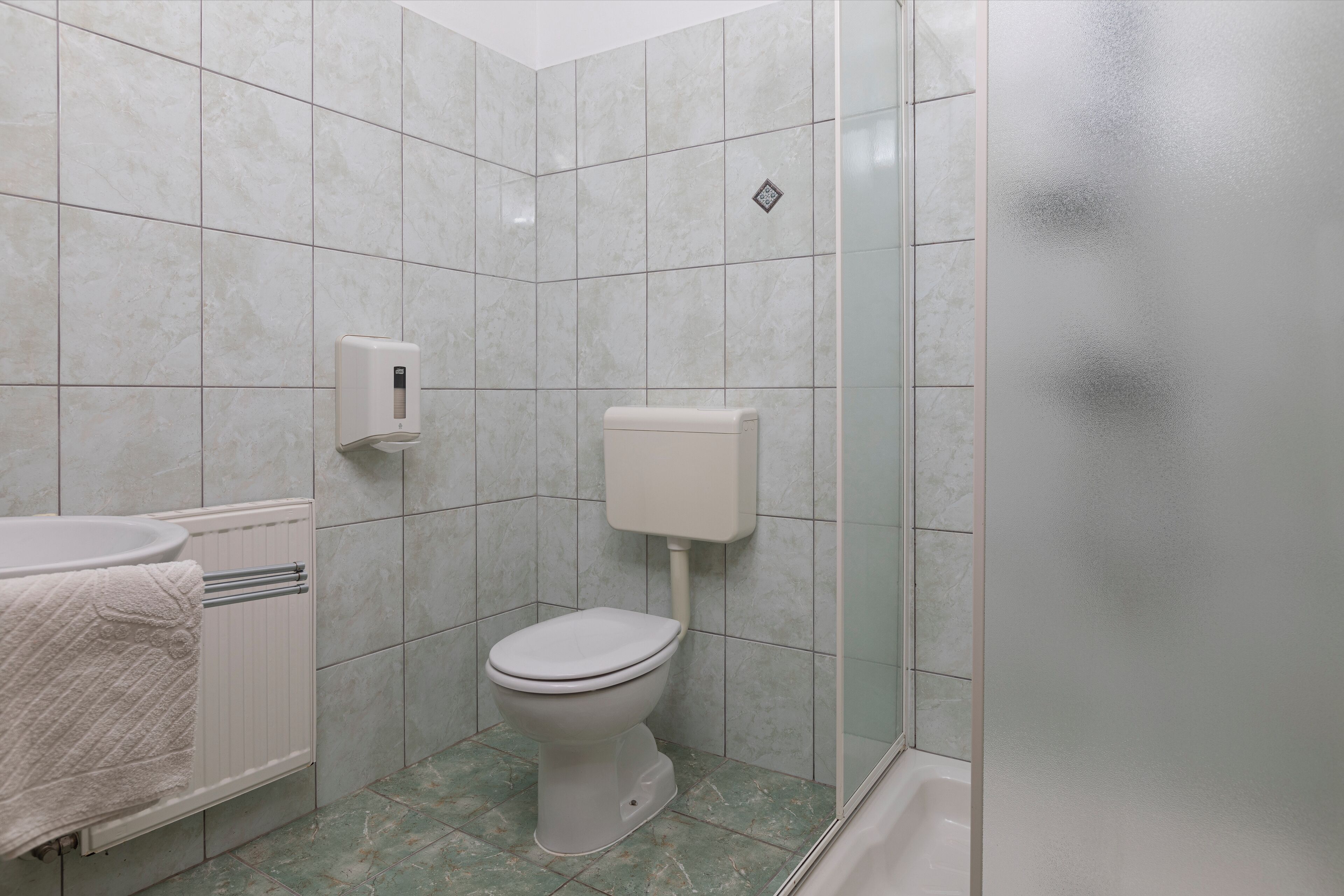 A bathroom with a toilet, a hand dryer, and a towel rack.