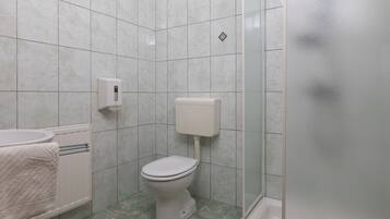 Un baño con inodoro, secamanos y toallero.