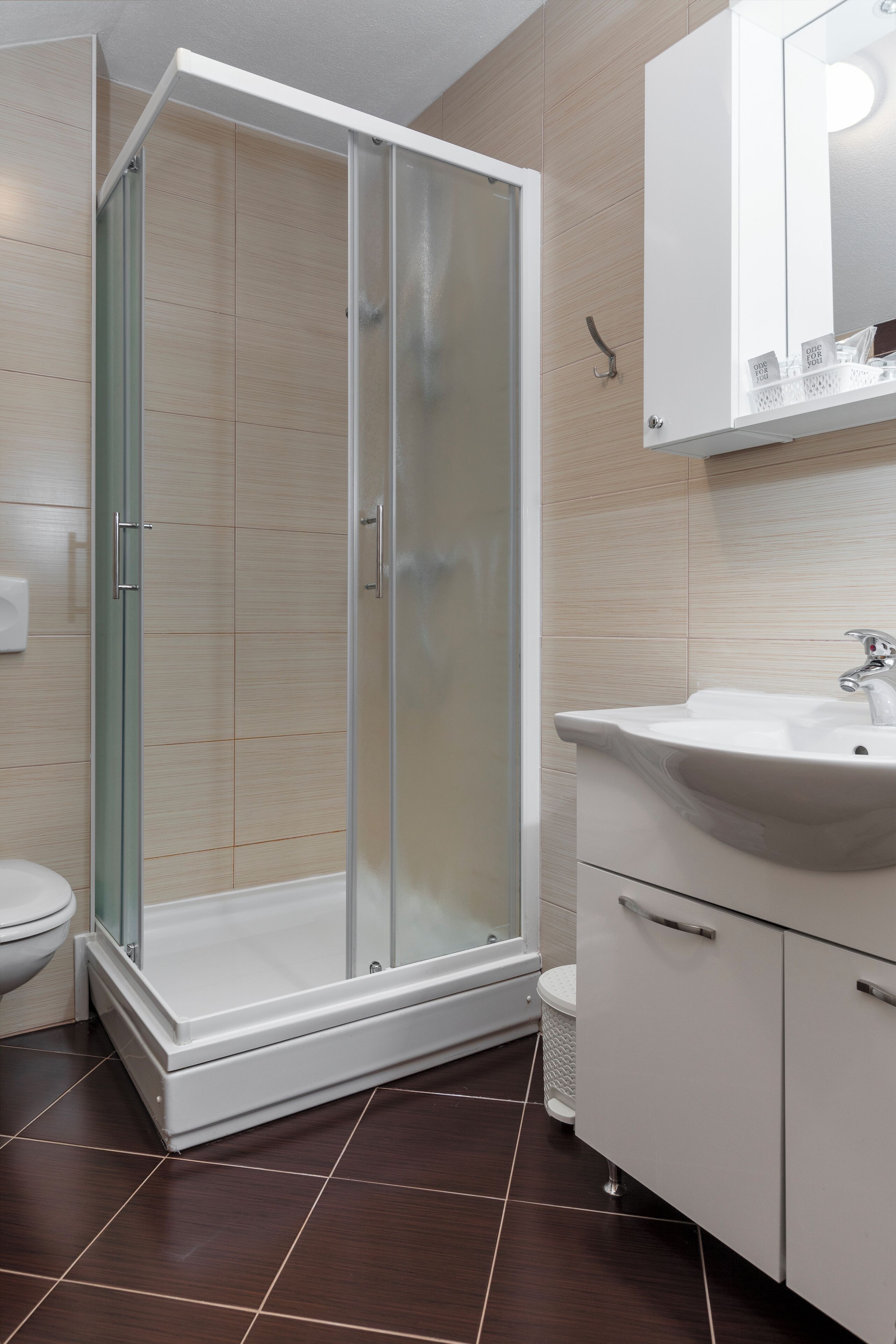 Un baño moderno con ducha de vidrio, un lavamanos blanco y un mueble con espejo.