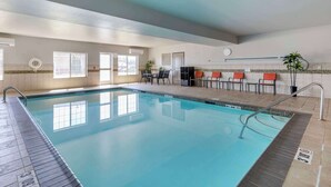 A swimming pool with a tiled deck, a sunroof, and a seating area with chairs. - Country Inn & Suites by Radisson, St. Peters, MO (St. Charles)