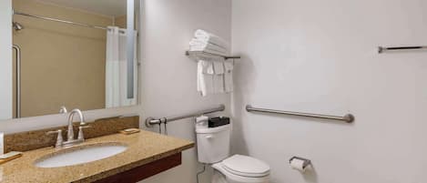 Baño con lavamanos, inodoro y barras de apoyo.