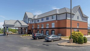 A hotel with a brick facade, multiple windows, and a parking lot with several cars.