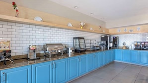 A modern kitchen with blue cabinets, white tiled backsplash, and various appliances.