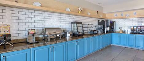 A modern kitchen with blue cabinets, white tiled backsplash, and various appliances.
