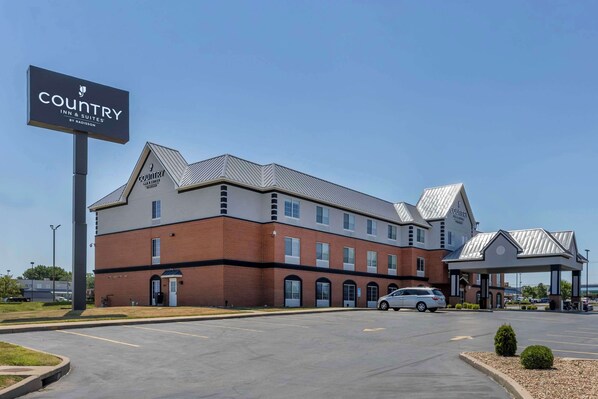 A Country Inn & Suites building with a brick facade, multiple windows, and a covered parking area.