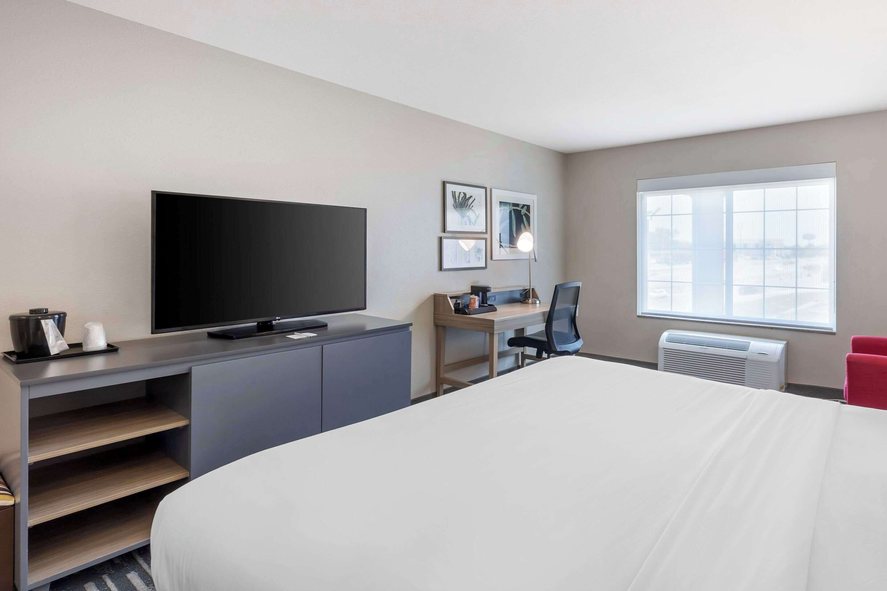 Habitación de hotel con una cama grande, un televisor de pantalla plana, un escritorio con una silla y una ventana con vistas.
