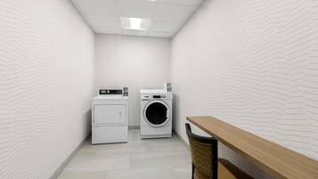 A laundry room with a washing machine, dryer, and a table.