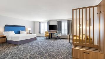 Habitació d'hotel amb un llit, escriptori, cadira, televisió i una separació de fusta.