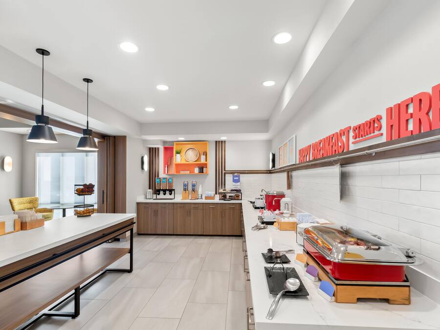 Una cocina moderna con barra de desayuno, armarios de madera y un cartel que dice 'HAPPY BREAKFAST STARTS HERE'.