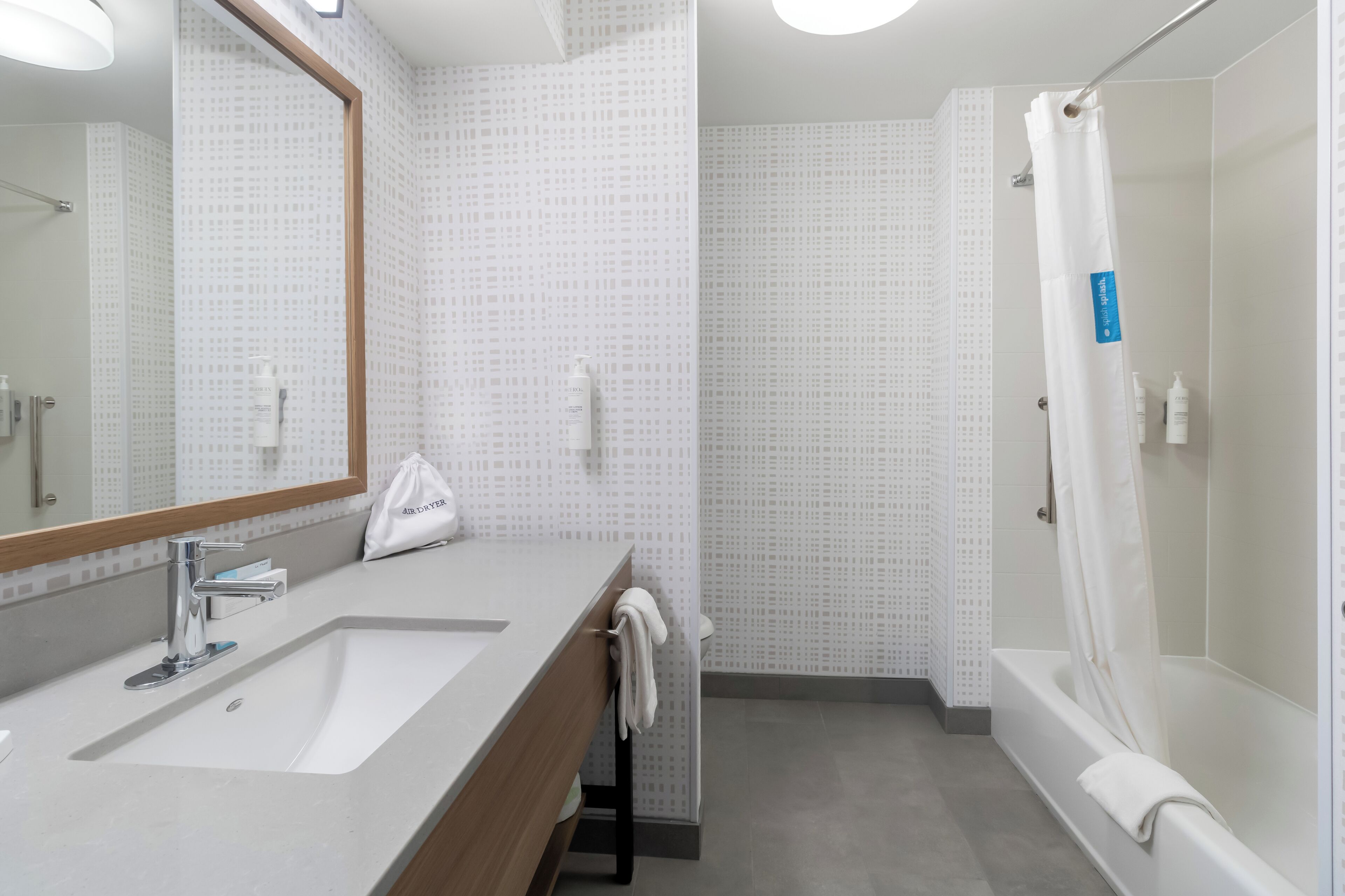 Un baño moderno con lavamanos, espejo y ducha.