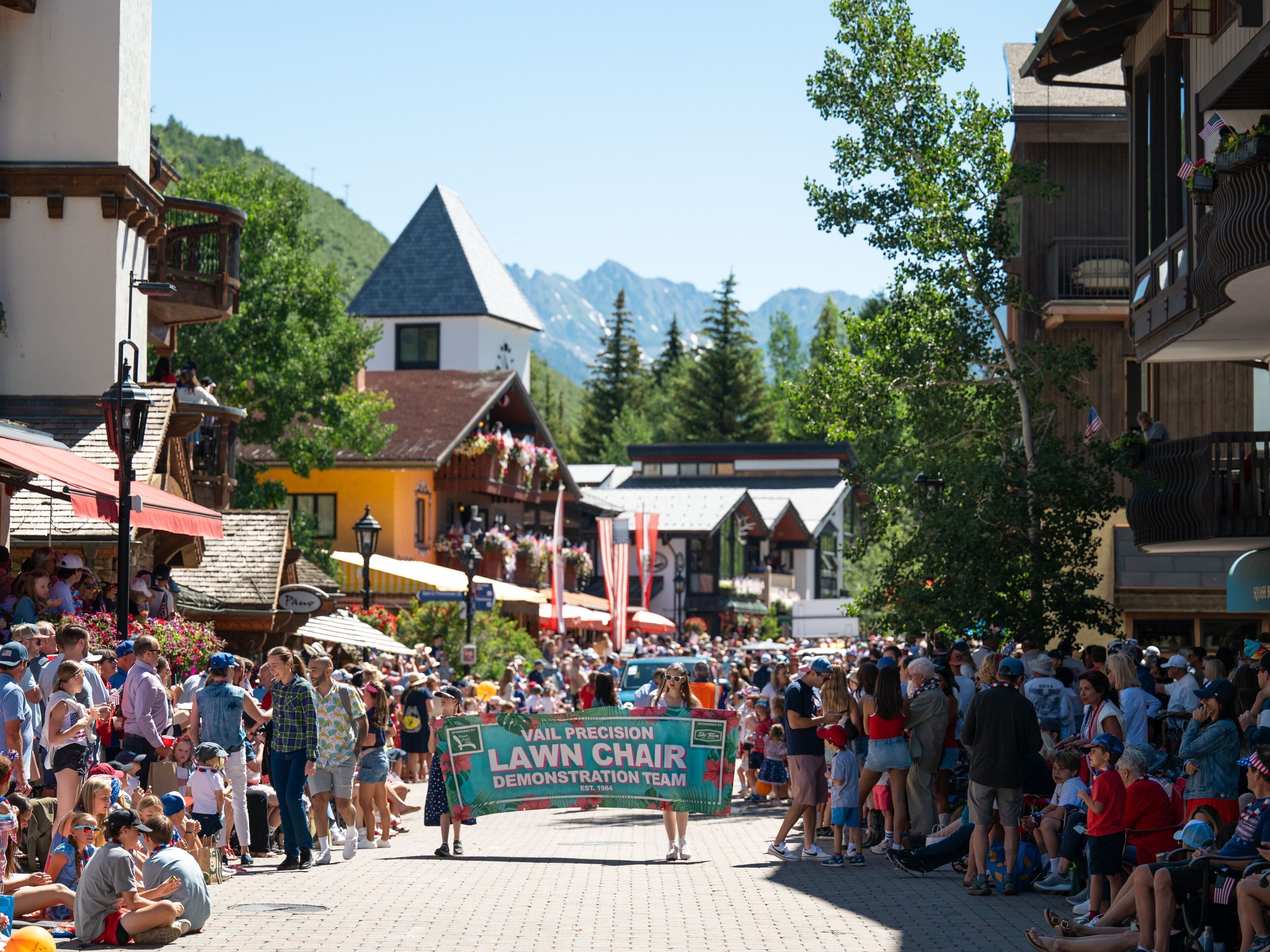 A crowded street with a lawn chair demonstration team.