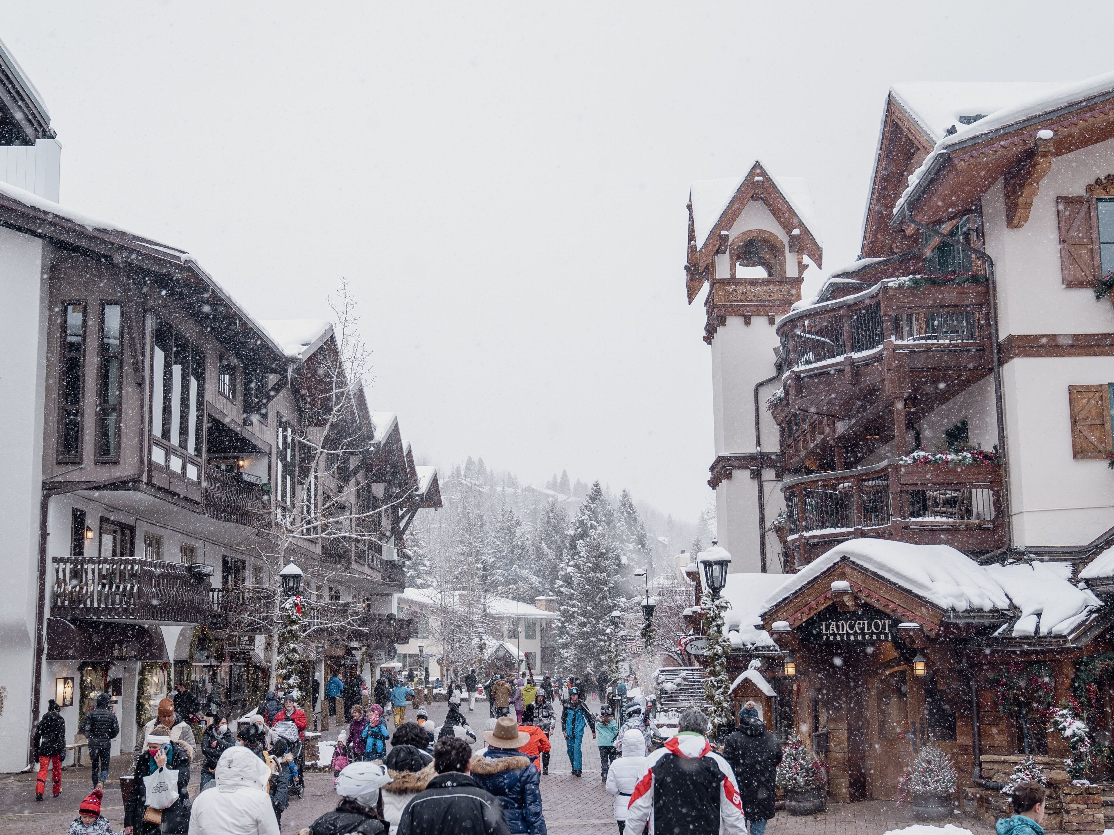 A snow-covered street with traditional European architecture, including a restaurant named "LADCELOT."