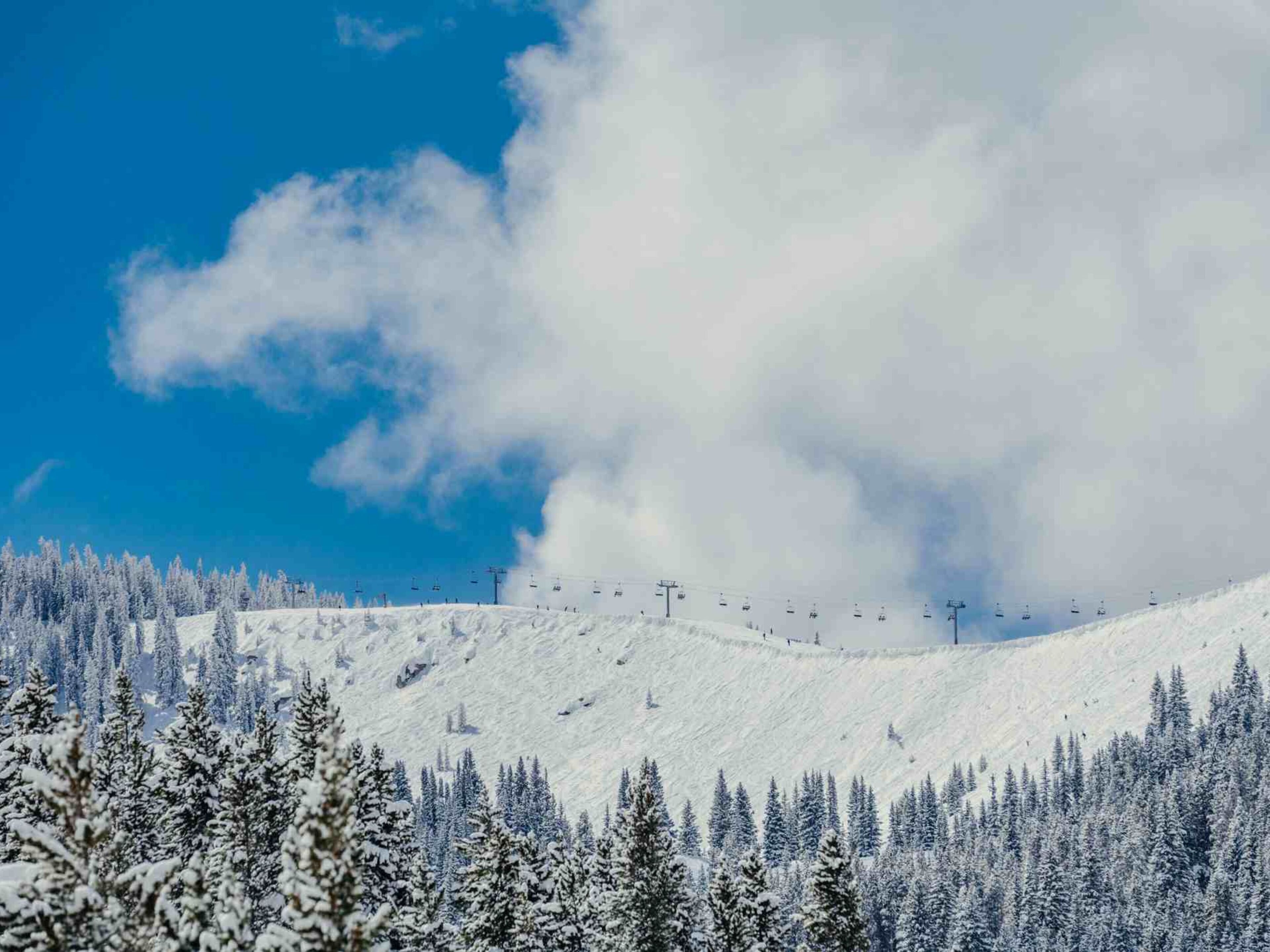 A snowy mountain landscape with a ski lift and snow-covered trees.