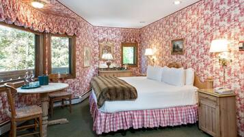 A bedroom with a bed, a desk, a chair, a nightstand, and a window.