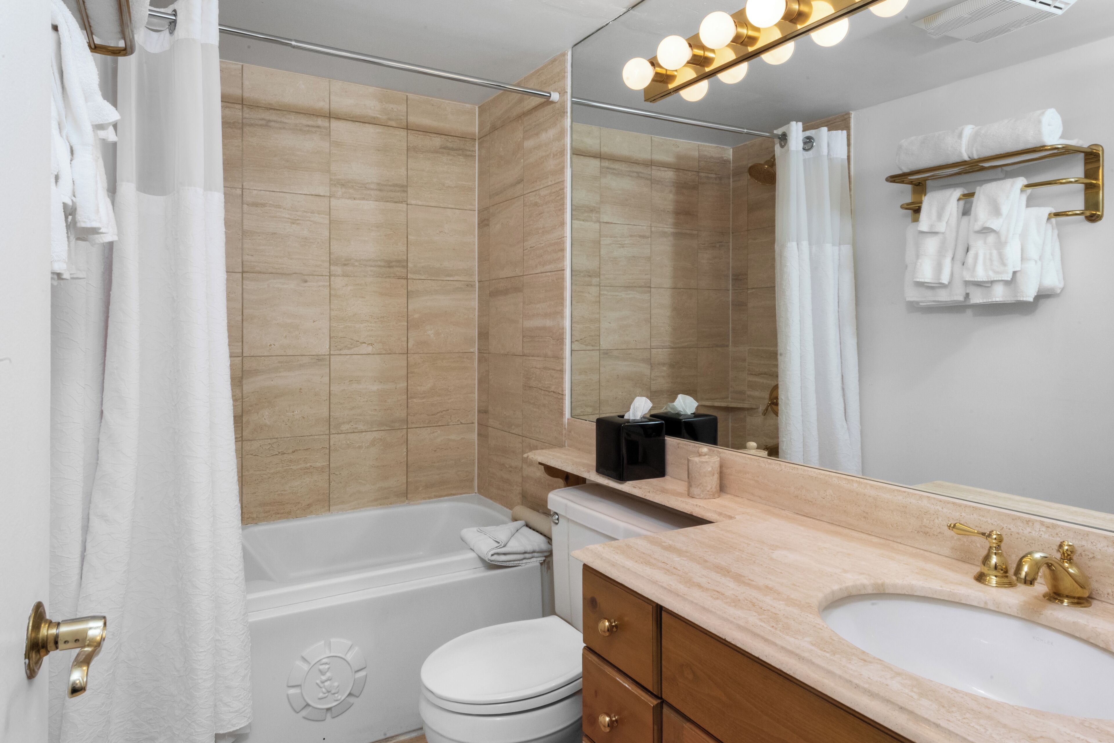 Ein modernes Badezimmer mit einer Badewanne, Toilette, Waschtisch und einem großen Spiegel.