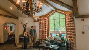 Un interior acogedor con suelo de piedra, un candelabro, una chimenea y un amplio ventanal con cortinas.