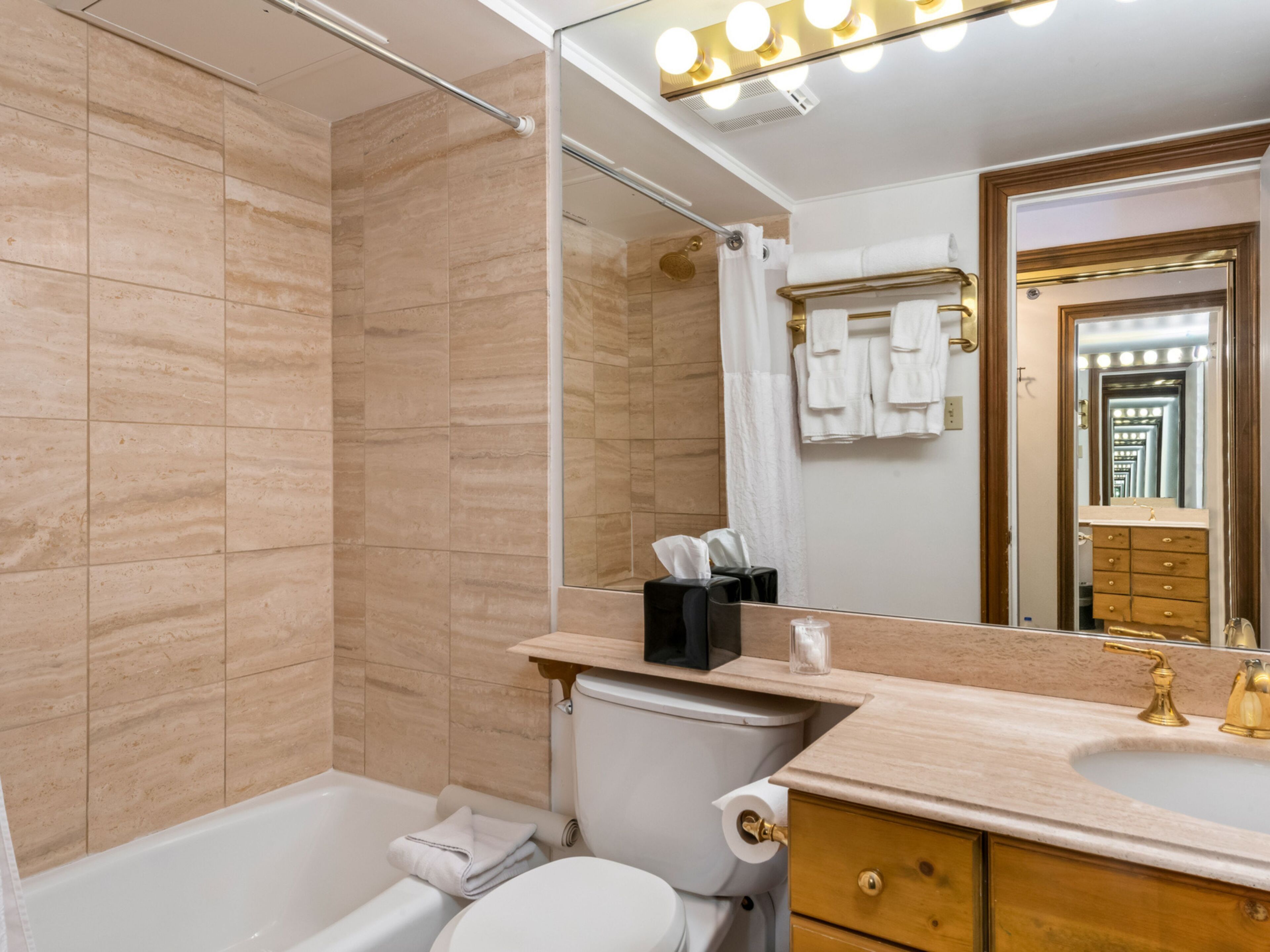 Un baño moderno con bañera, inodoro y tocador con espejo.