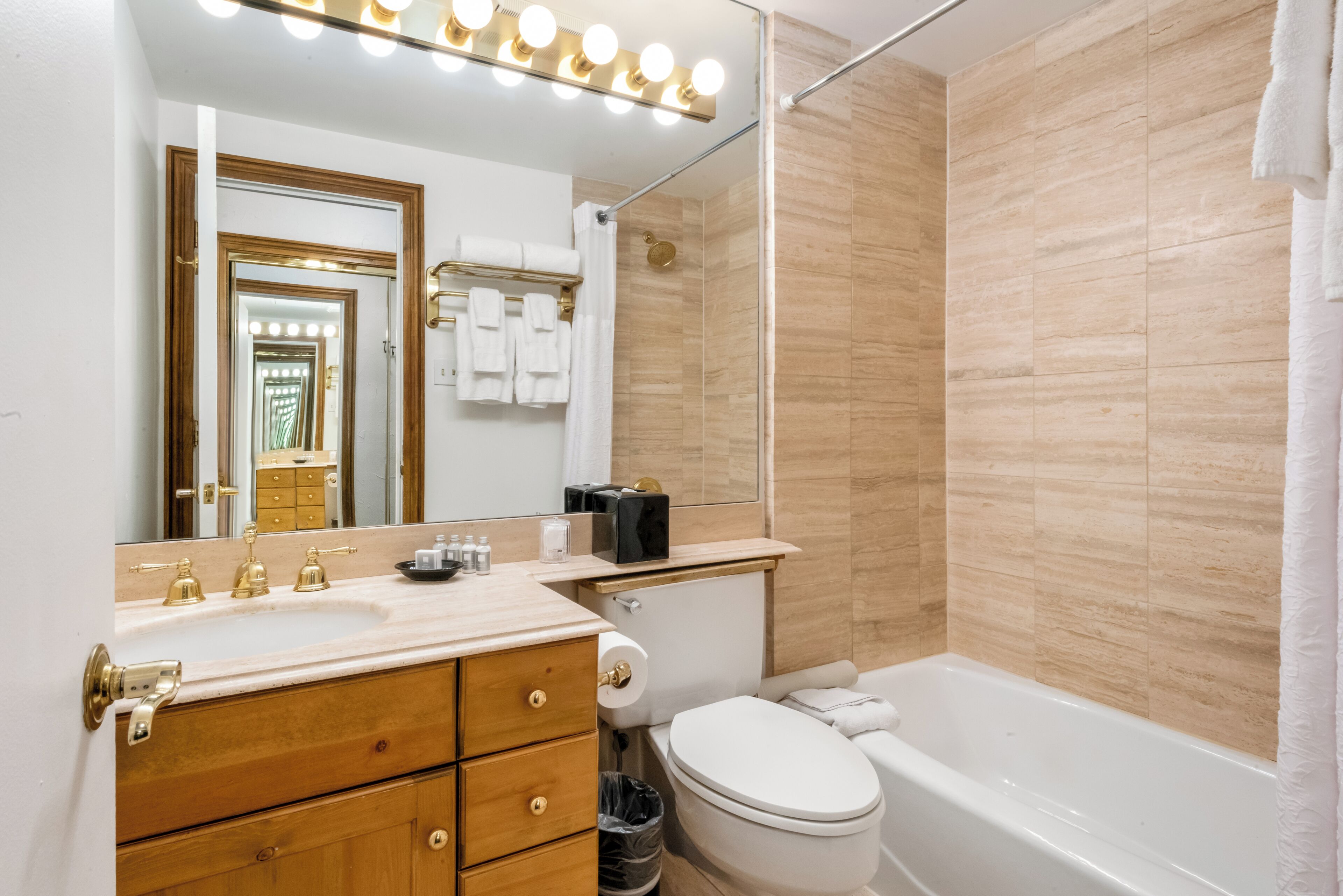 A bathroom with a vanity, sink, mirror, toilet, and bathtub.