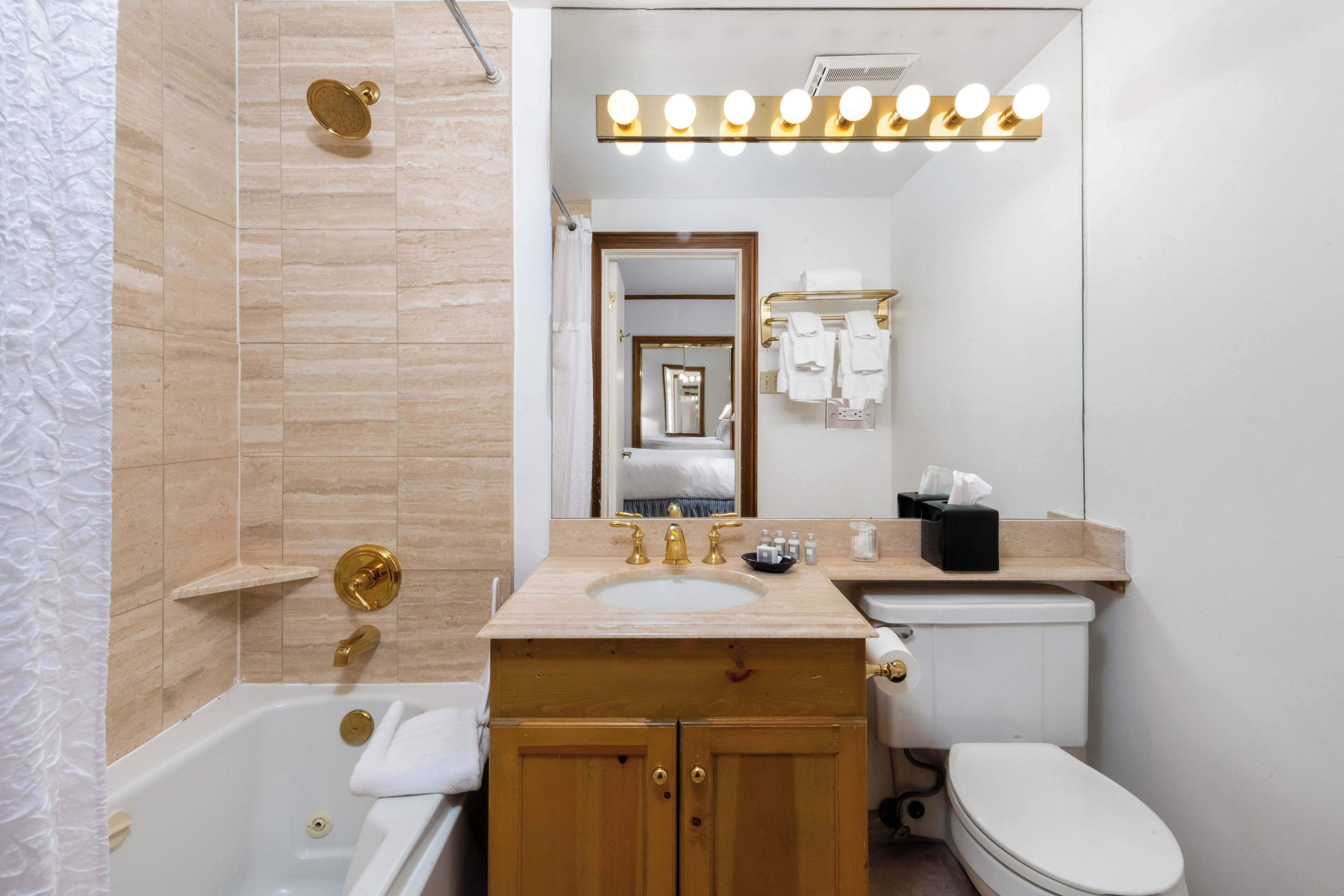 A bathroom with a bathtub, a sink, a toilet, a vanity with a mirror, and a shower area.