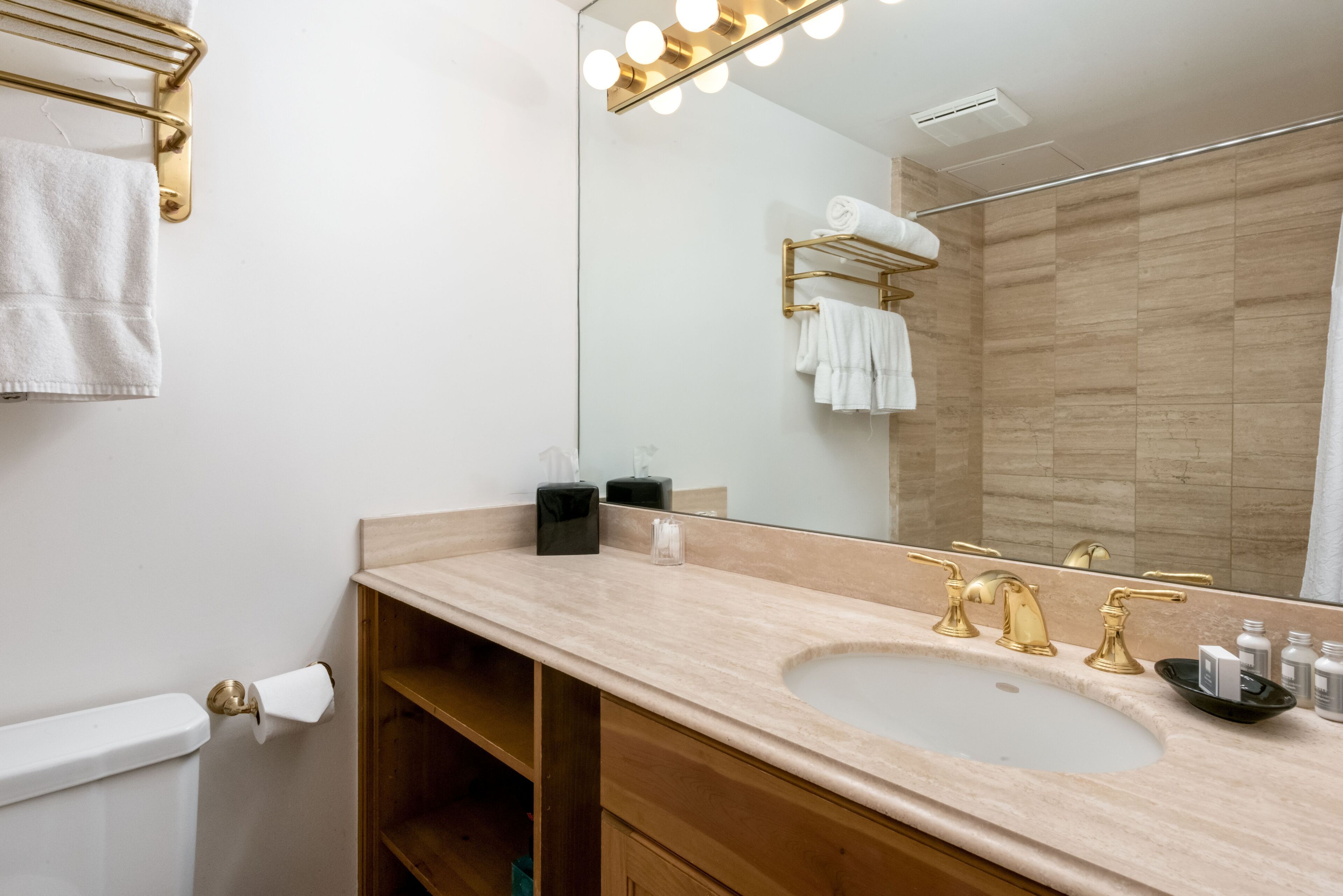 A bathroom with a sink, mirror, towel rack, and a shower area.