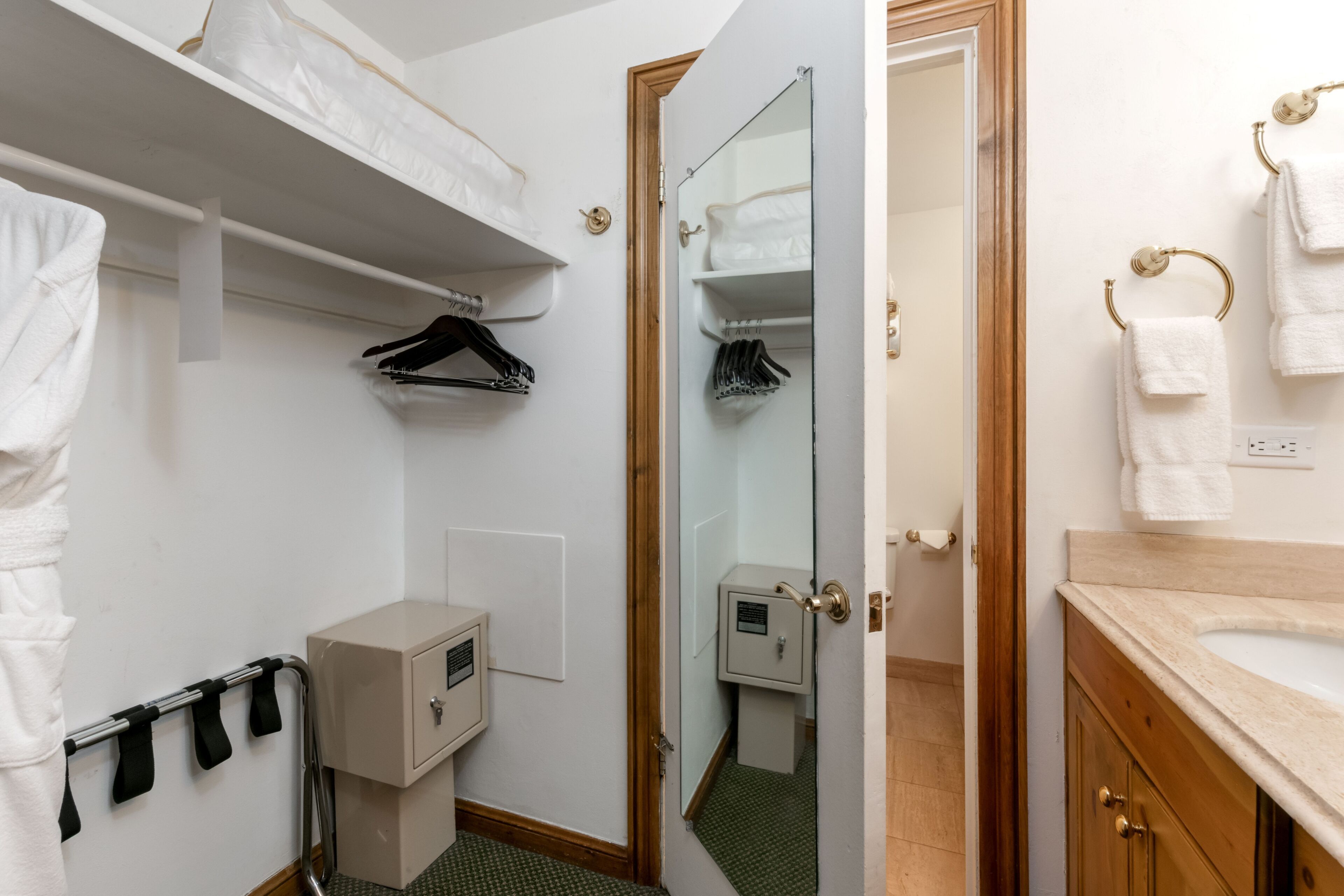 A hotel bathroom with a shower, a sink, a mirror, and a towel rack.