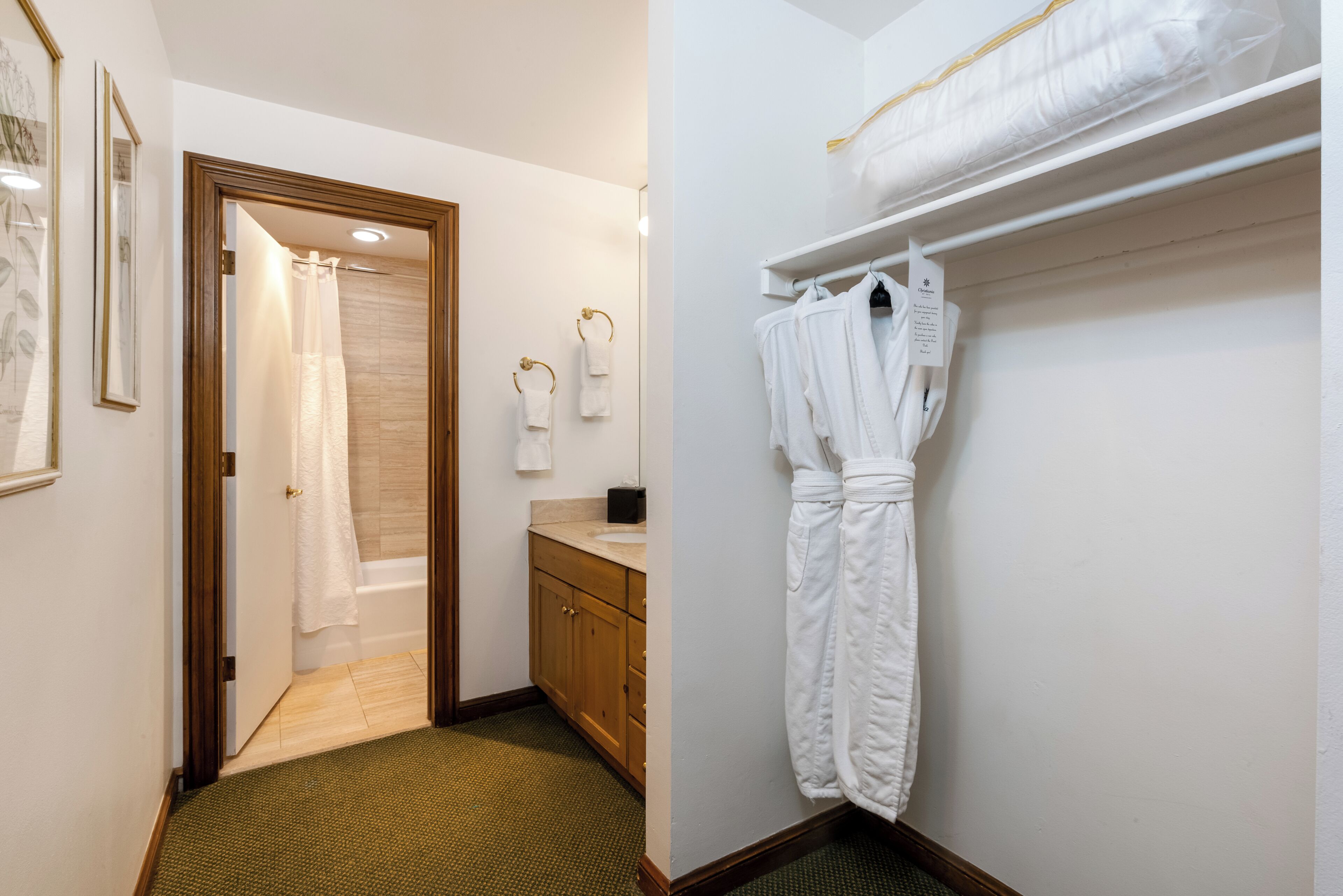 Une salle de bain d’hôtel avec une douche, un meuble-lavabo en bois et un porte-peignoir.