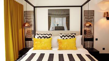 Quarto de hotel com cama, cortinas, um quadro e duas luminárias.