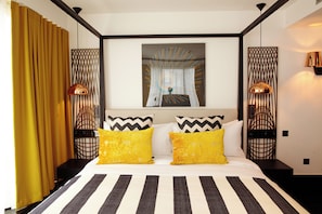 Une chambre d’hôtel avec un lit, des rideaux, un tableau et deux lampes.