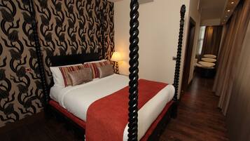Ein Himmelbett mit roter Bettdecke, Wandpapier mit Muster und Holzboden.