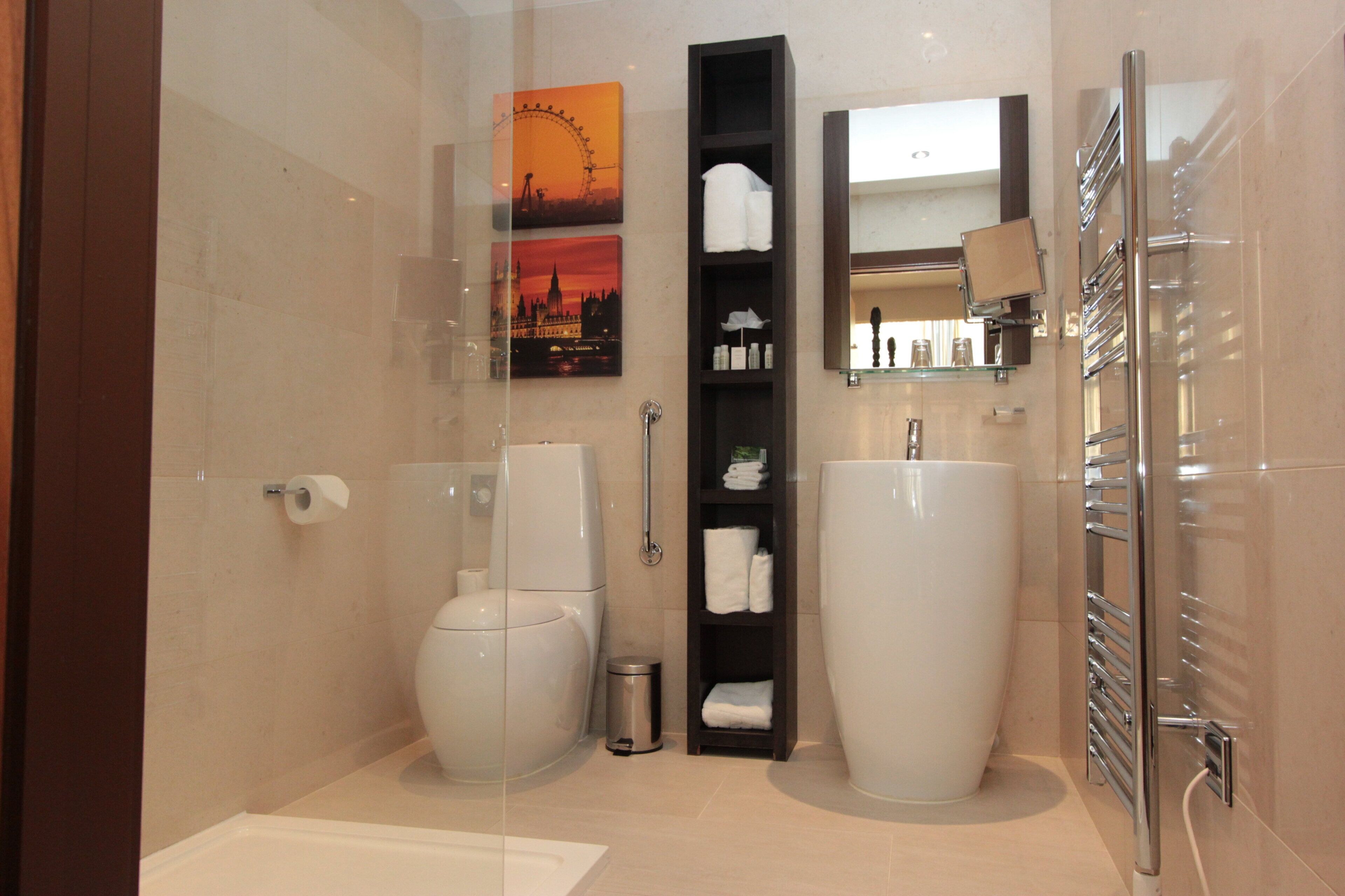 Une salle de bain moderne avec une douche à parois de verre, des toilettes, un lavabo et une étagère contenant des articles de toilette.